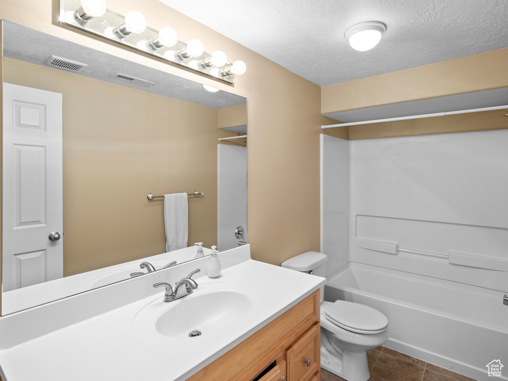 Full bathroom with a textured ceiling, oversized vanity, shower / washtub combination, tile floors, and toilet