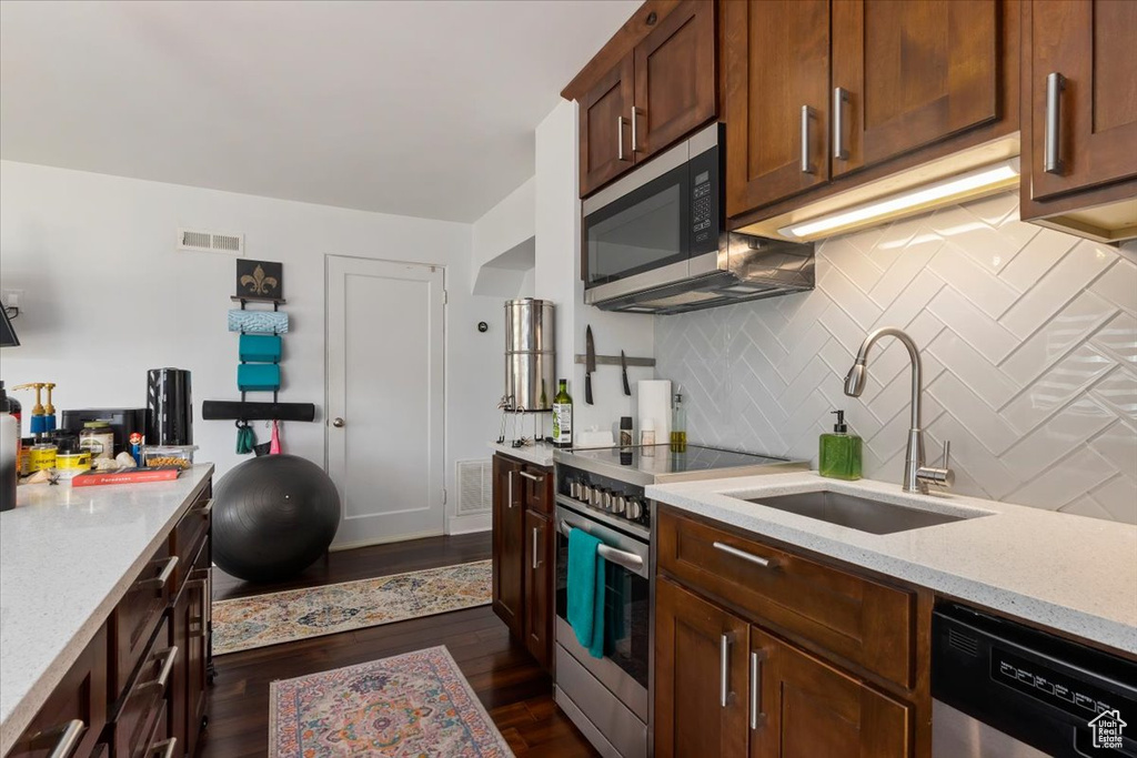 Kitchen with dark hardwood / wood-style floors, sink, stainless steel appliances, and tasteful backsplash