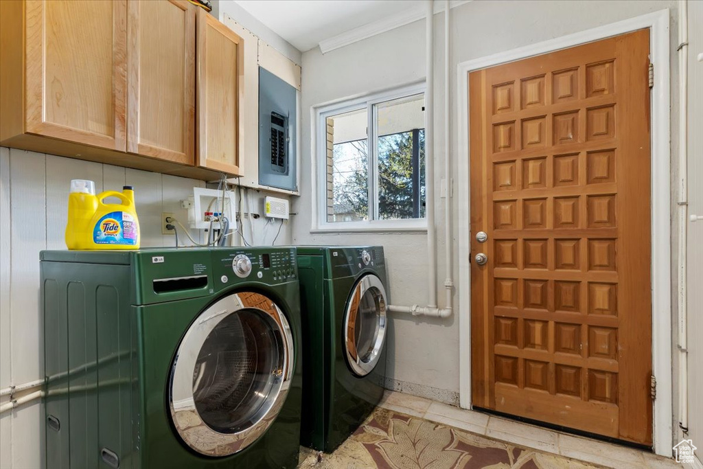 Clothes washing area featuring washer and dryer, cabinets, light tile floors, crown molding, and washer hookup