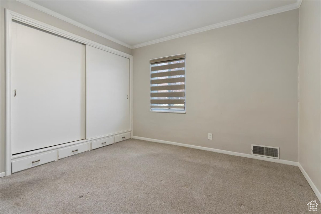 Unfurnished room featuring ornamental molding and light carpet