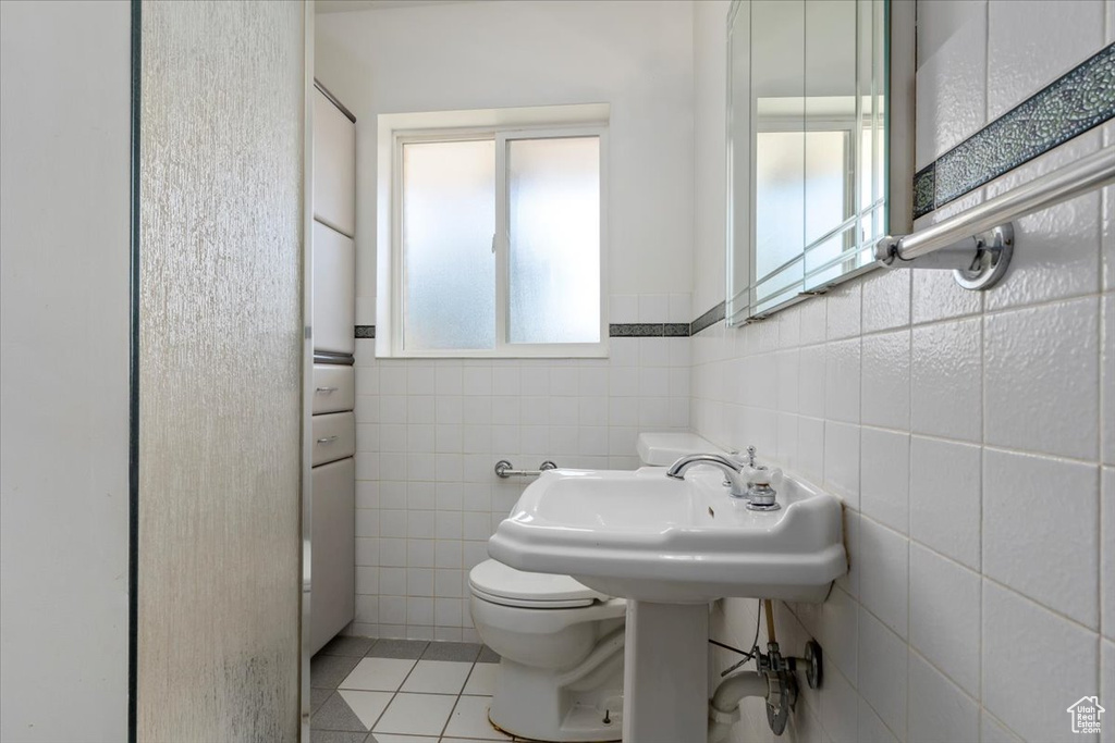 Bathroom with tile walls, tile floors, and toilet