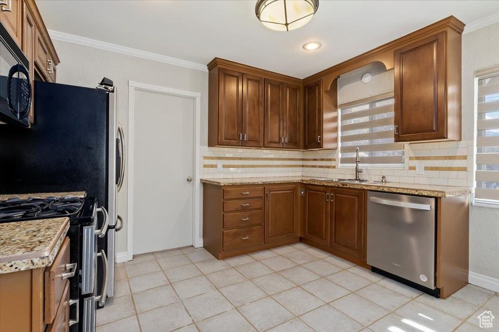 Kitchen featuring tasteful backsplash, appliances with stainless steel finishes, sink, and light tile flooring