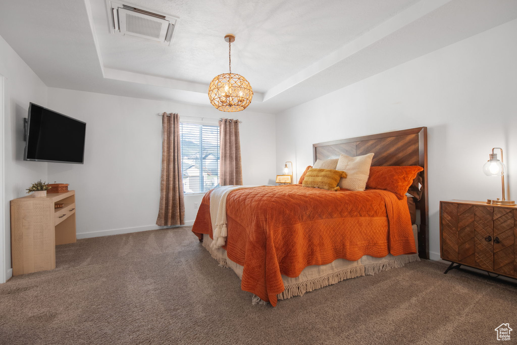 Carpeted bedroom with a raised ceiling and a chandelier