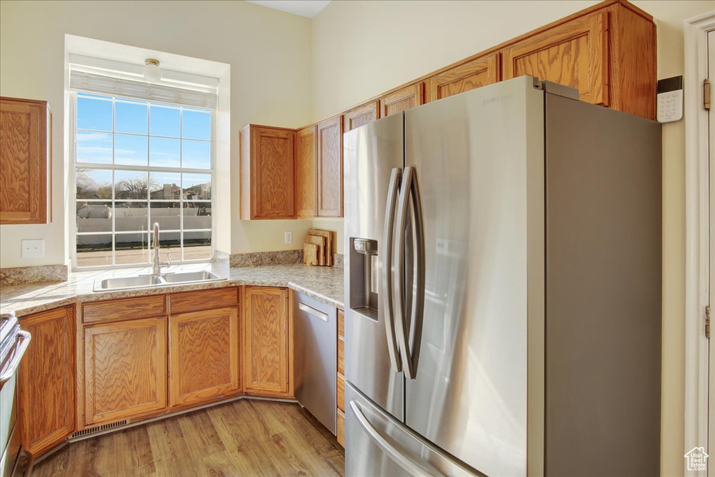 Kitchen featuring light hardwood / wood-style flooring, sink, stainless steel appliances, and light stone countertops