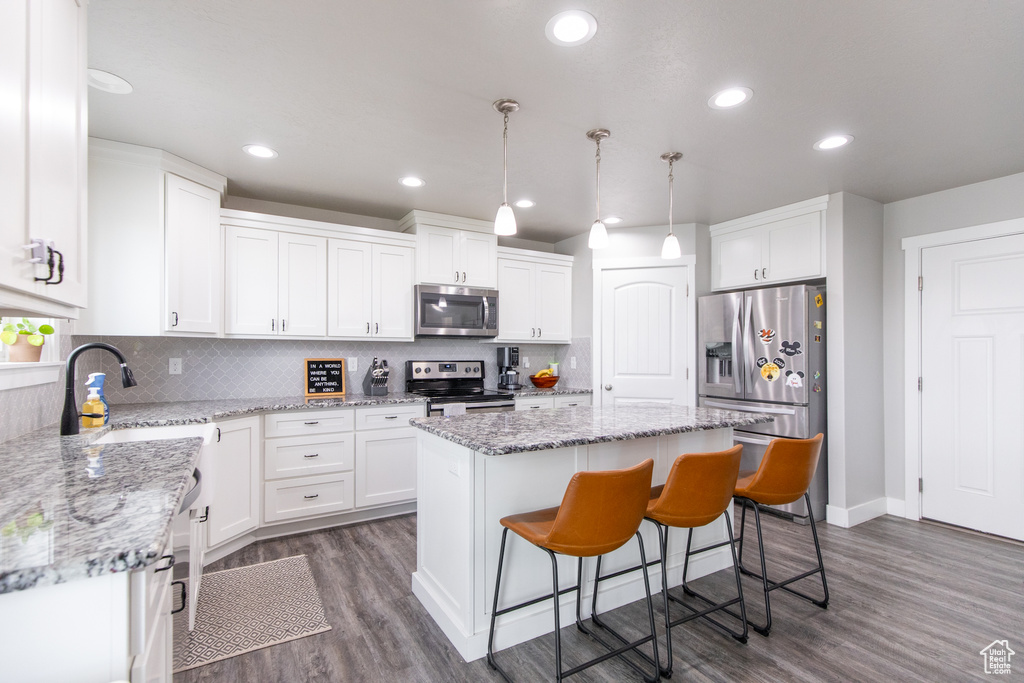 Kitchen featuring tasteful backsplash, stainless steel appliances, a center island, and white cabinetry