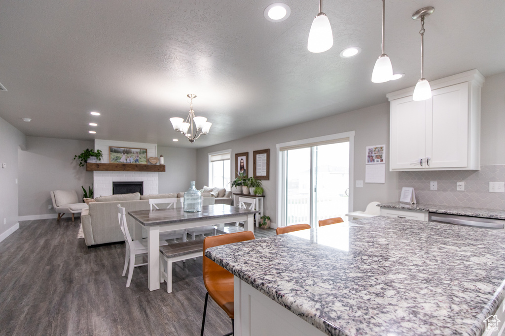 Kitchen featuring white cabinets, tasteful backsplash, dark hardwood / wood-style flooring, and light stone countertops