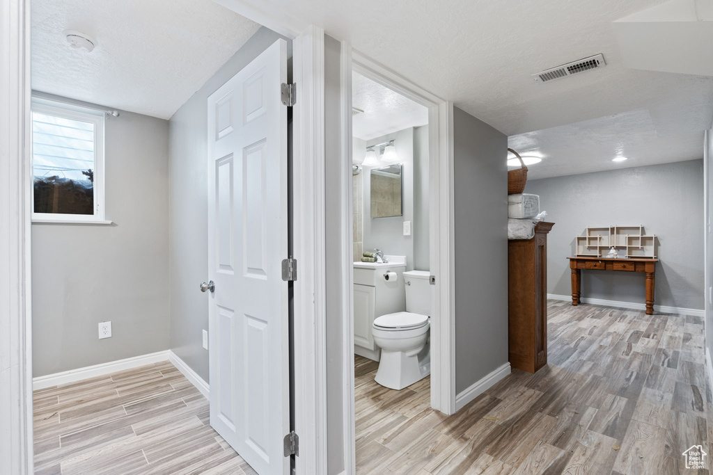 Bathroom featuring toilet, vanity, hardwood / wood-style floors, and lofted ceiling