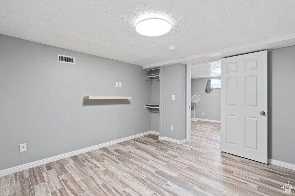 Basement with a textured ceiling and light hardwood / wood-style flooring