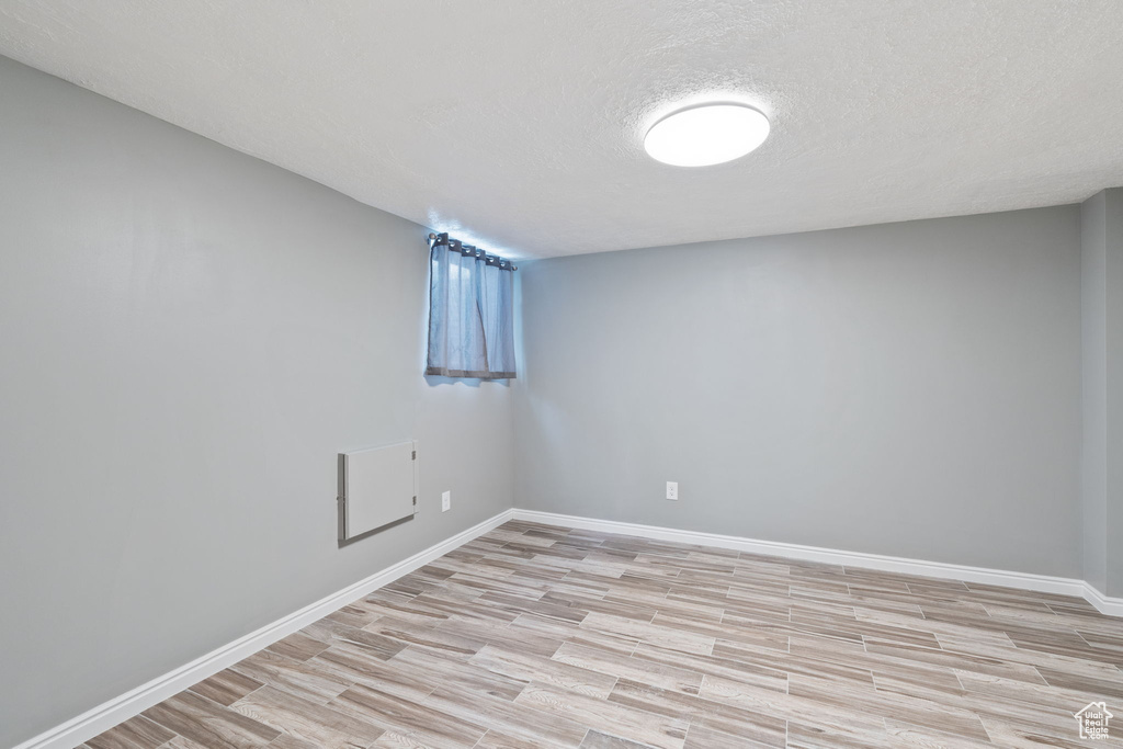 Spare room featuring a textured ceiling and light hardwood / wood-style flooring