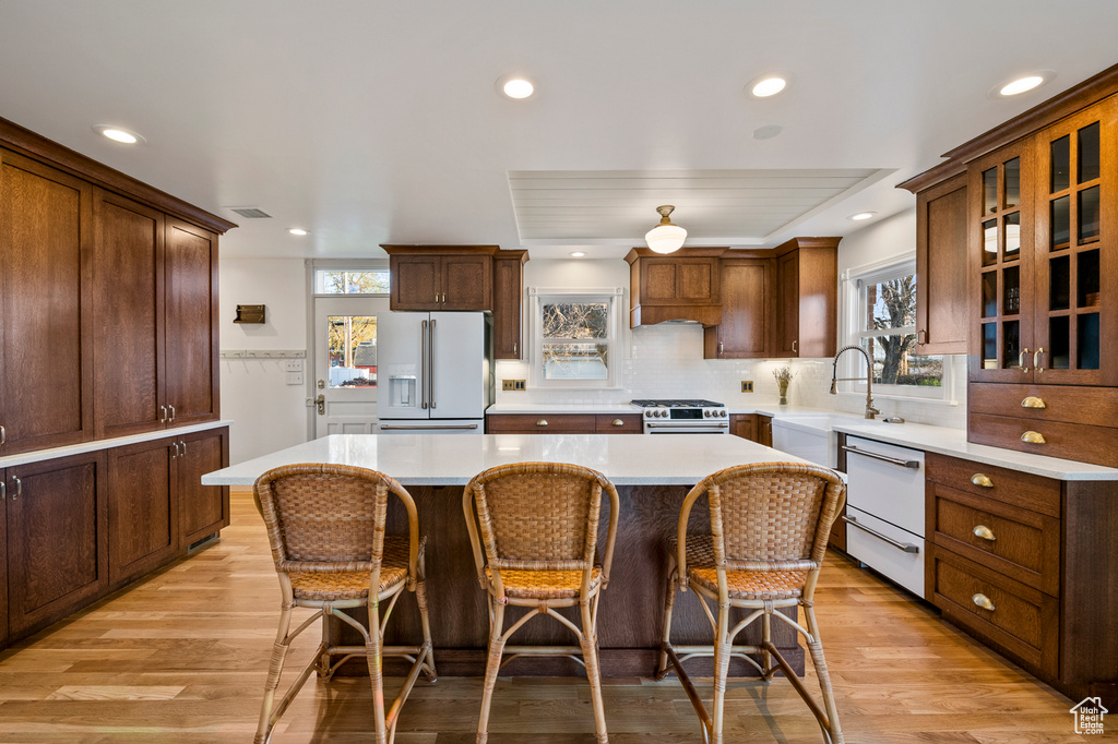 Kitchen with a kitchen island, plenty of natural light, white appliances, and light wood-type flooring