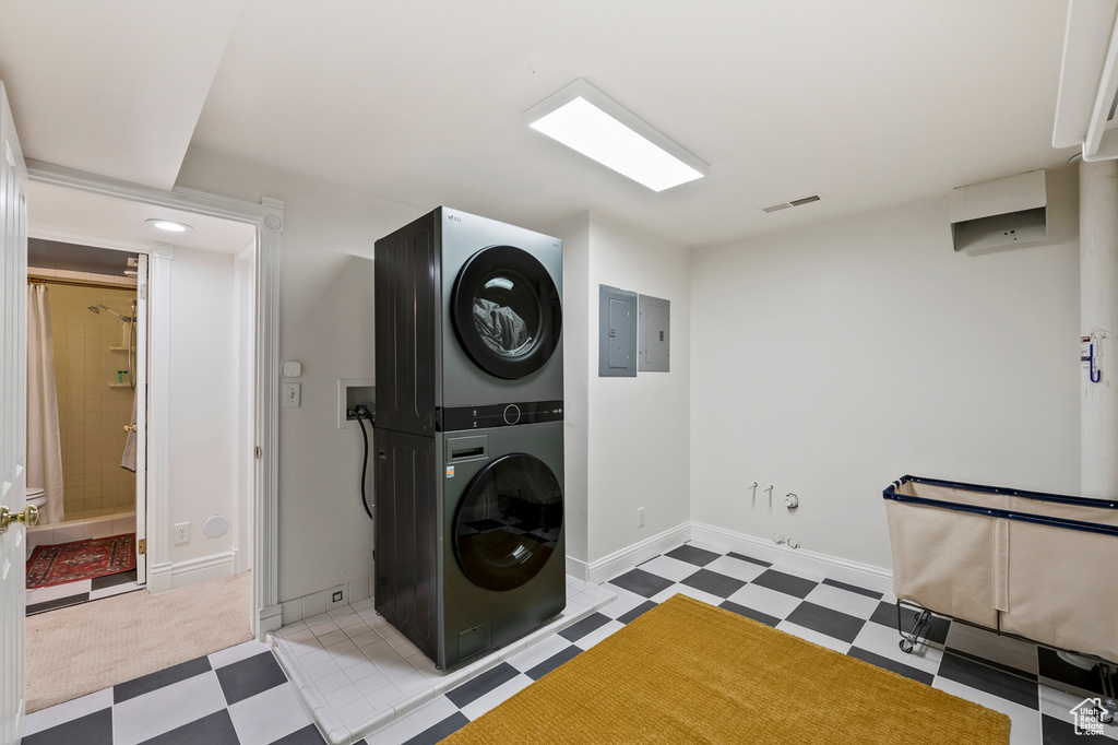 Laundry room with hookup for a washing machine, stacked washer and dryer, and light tile floors