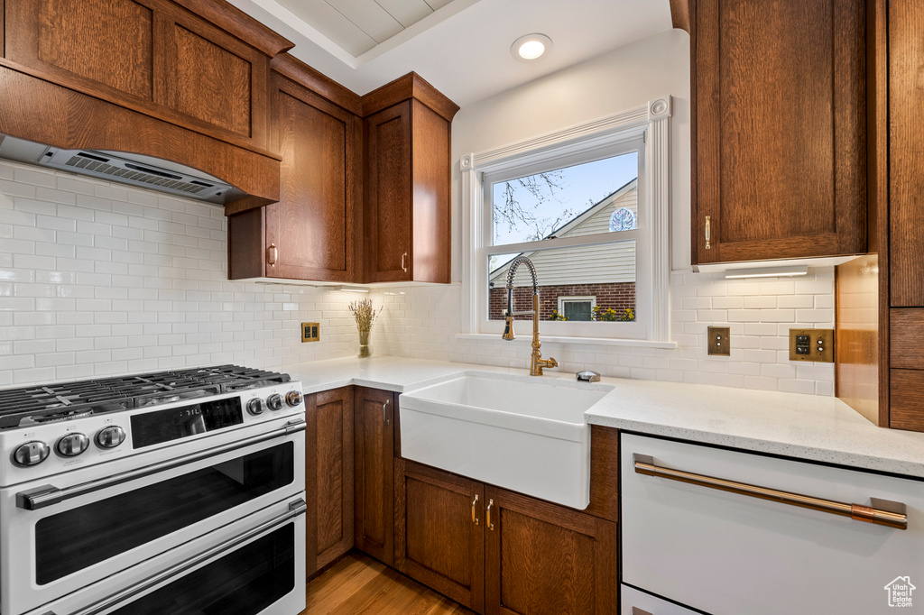Kitchen featuring sink, double oven range, tasteful backsplash, and light wood-type flooring