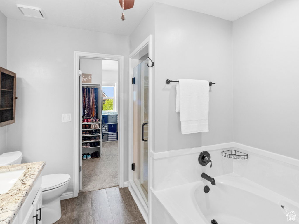 Full bathroom with hardwood / wood-style flooring, vanity, toilet, and separate shower and tub
