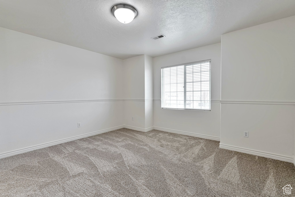 Spare room with light carpet and a textured ceiling