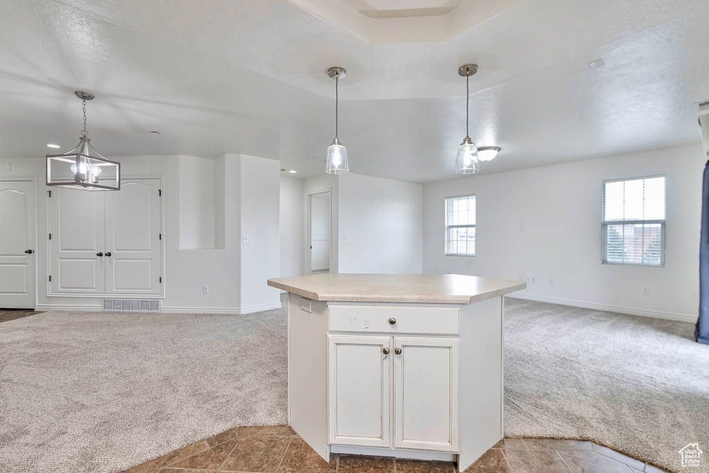 Kitchen with light carpet, white cabinets, a notable chandelier, and decorative light fixtures