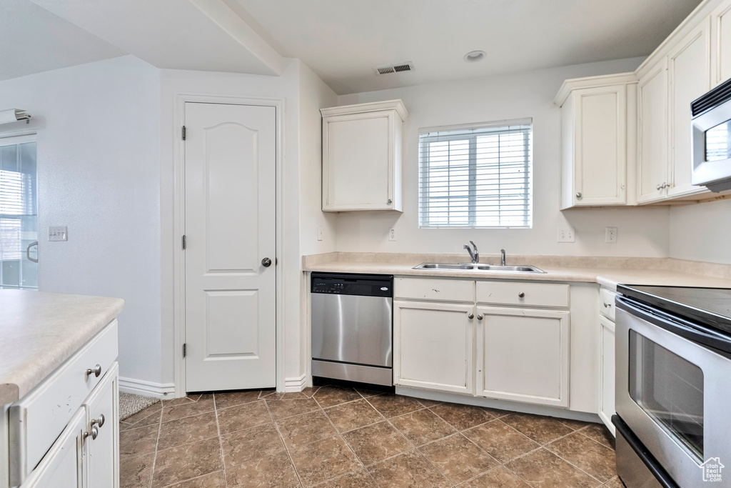 Kitchen with a healthy amount of sunlight, dishwasher, white cabinetry, and tile flooring