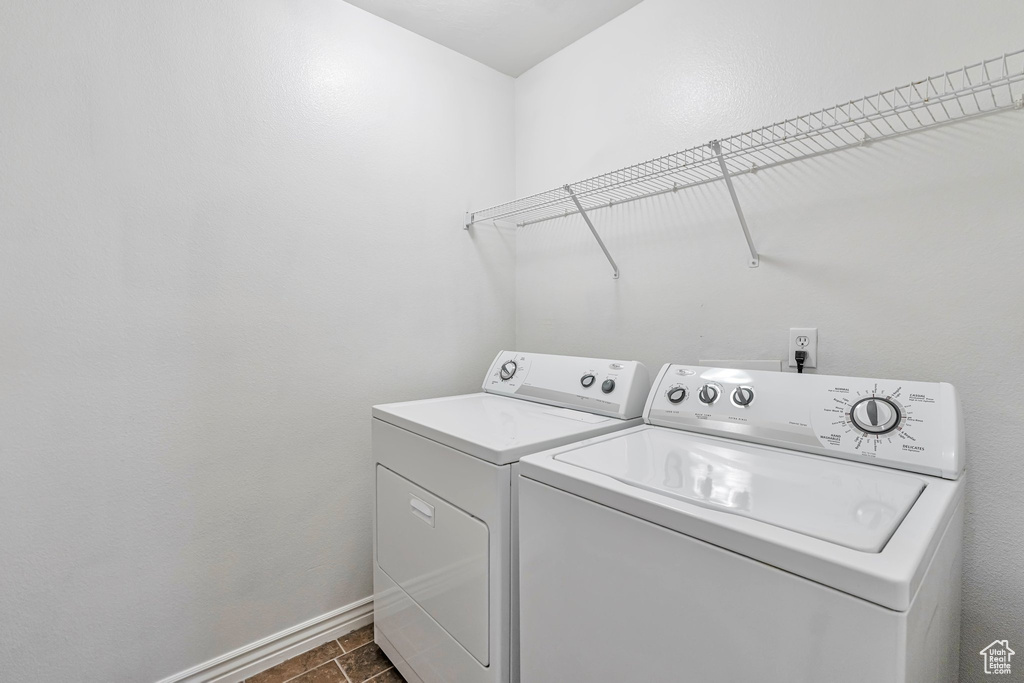 Clothes washing area featuring dark tile floors and washing machine and clothes dryer