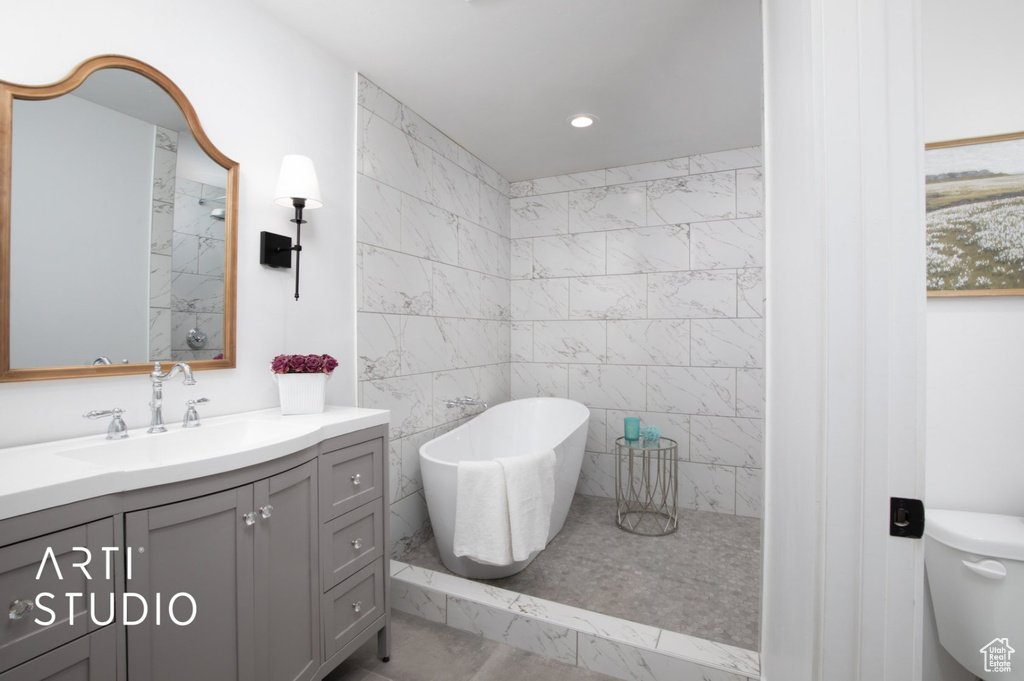 Bathroom featuring tiled shower, tile walls, toilet, tile floors, and vanity