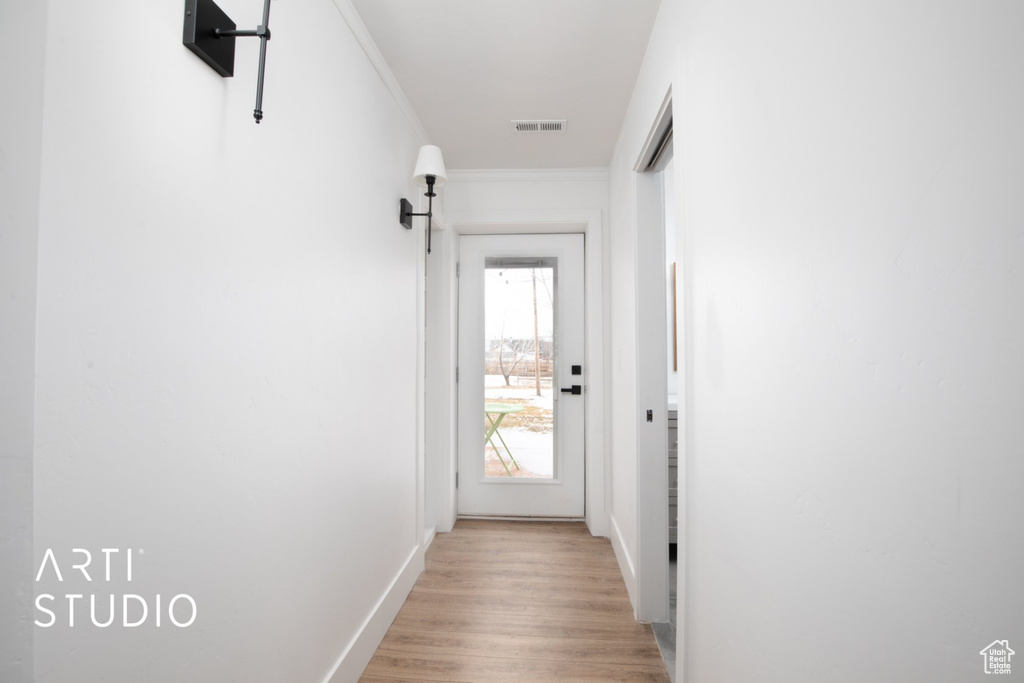 Doorway to outside featuring ornamental molding and light hardwood / wood-style floors