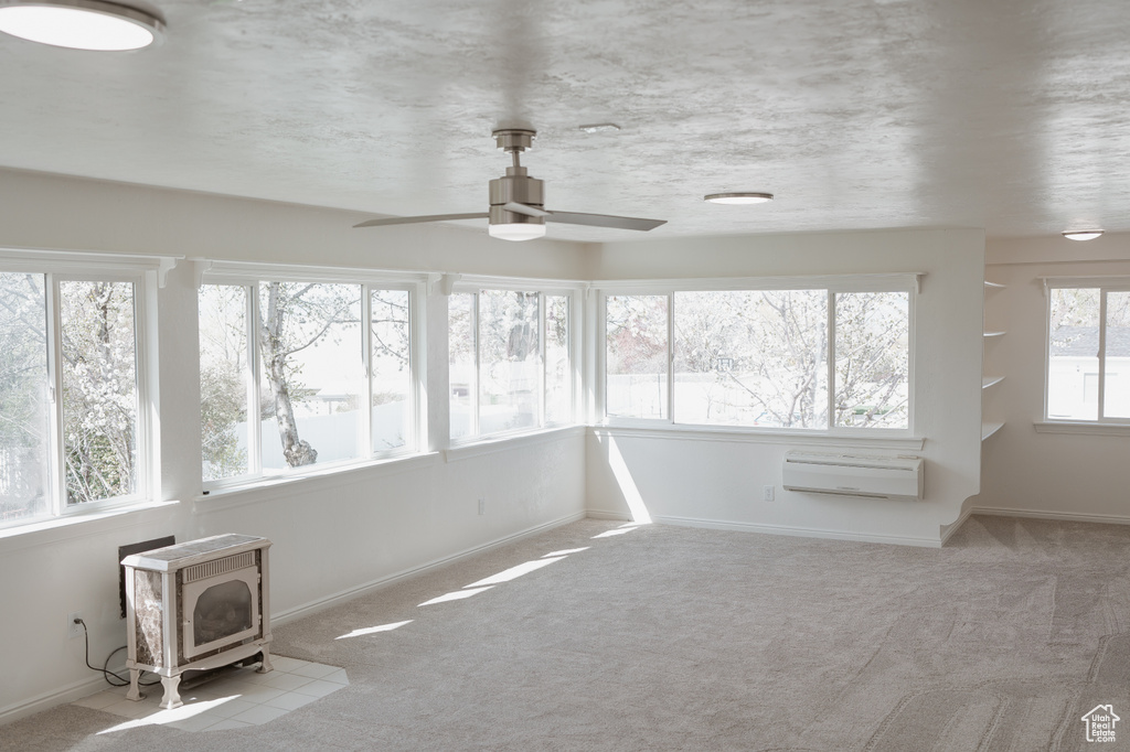 Unfurnished sunroom featuring a wood stove and ceiling fan