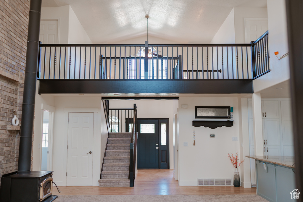 Entryway featuring high vaulted ceiling, light hardwood / wood-style floors, and a wood stove
