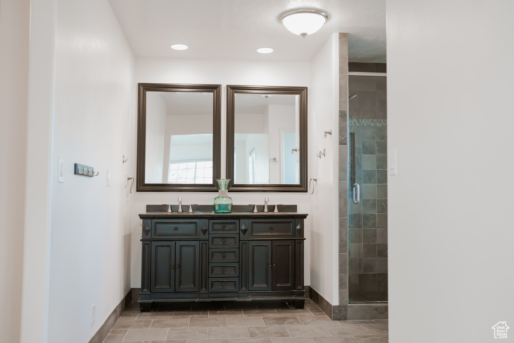 Bathroom featuring tile floors, a shower with shower door, double sink, and large vanity