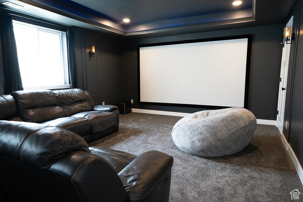 Carpeted home theater featuring a raised ceiling