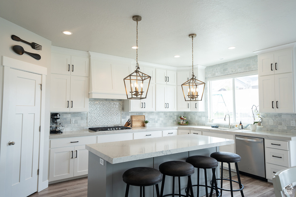 Kitchen with white cabinets, a center island, stainless steel appliances, and pendant lighting