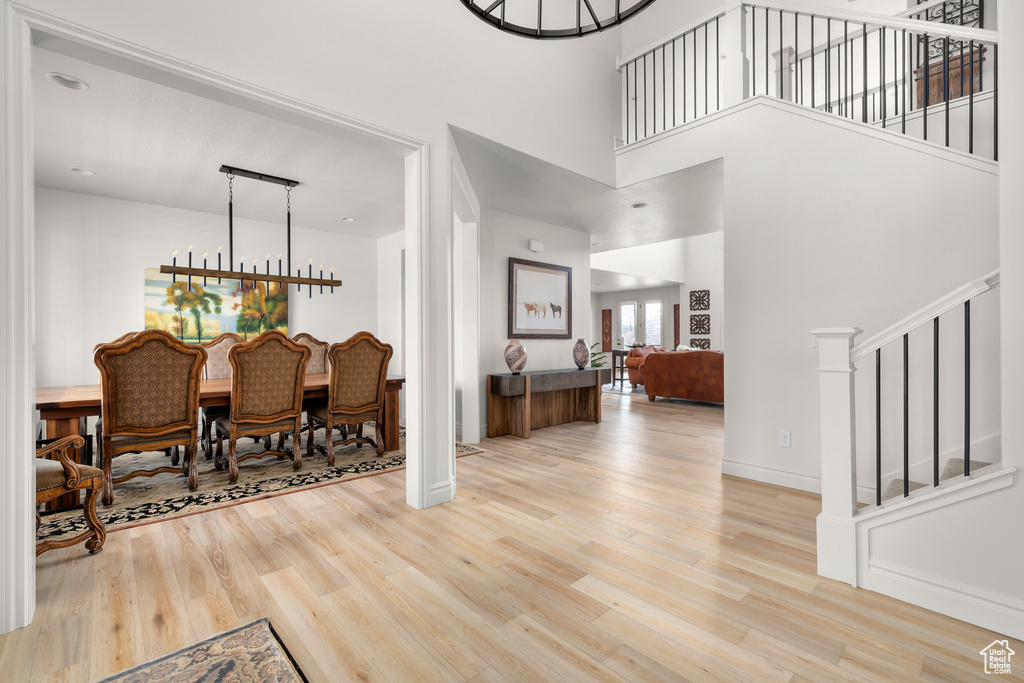 Foyer with light hardwood / wood-style flooring, an inviting chandelier, and a high ceiling
