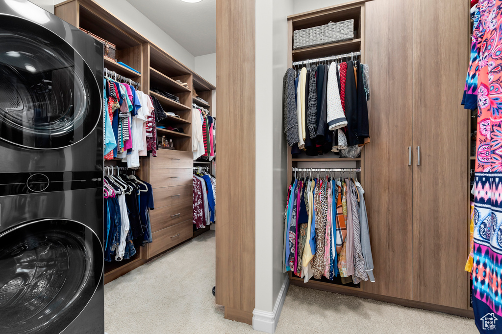 Spacious closet with light carpet and stacked washer and clothes dryer