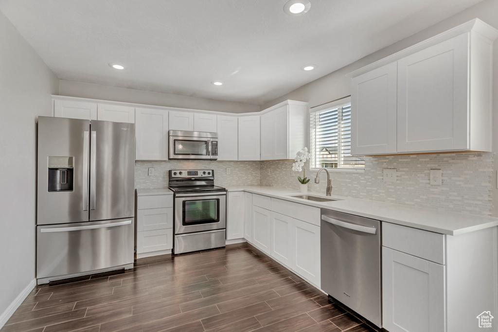 Kitchen featuring white cabinets, sink, backsplash, and stainless steel appliances