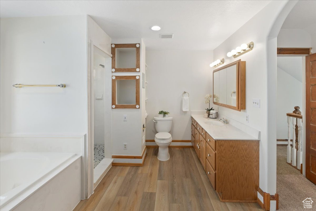 Full bathroom with vanity, separate shower and tub, toilet, and hardwood / wood-style flooring