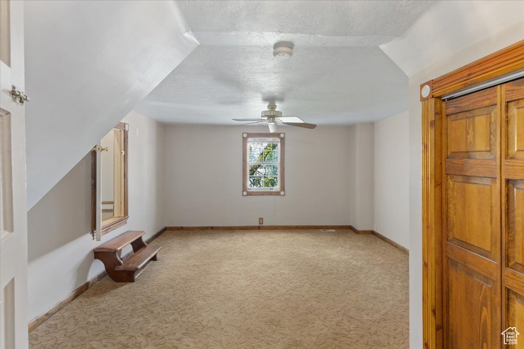 Additional living space featuring light colored carpet, a textured ceiling, and ceiling fan