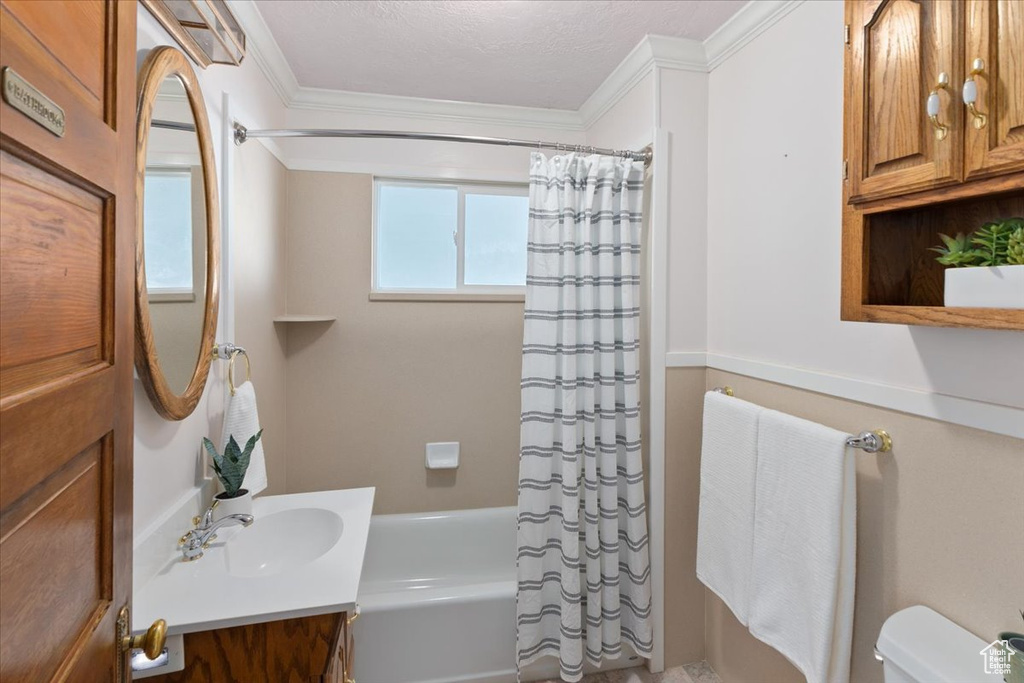 Full bathroom featuring shower / bath combo with shower curtain, a textured ceiling, crown molding, toilet, and vanity