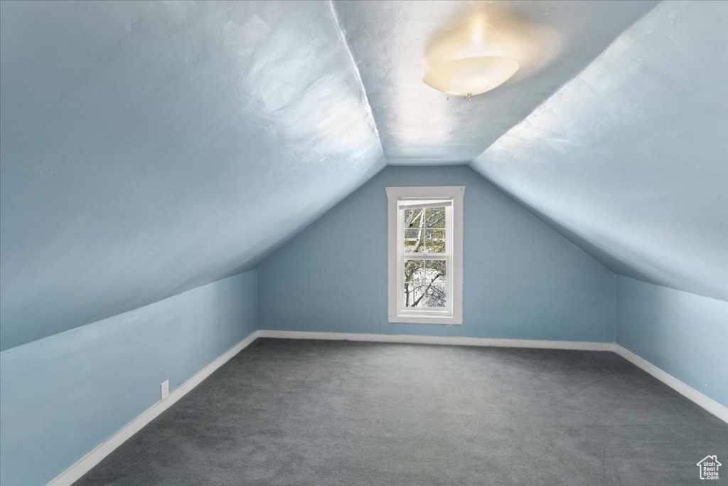 Bonus room featuring dark carpet and vaulted ceiling