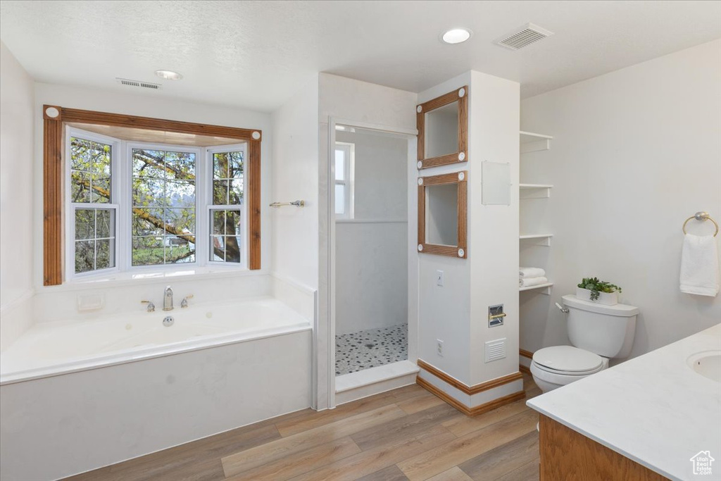 Full bathroom with independent shower and bath, vanity, hardwood / wood-style flooring, and toilet