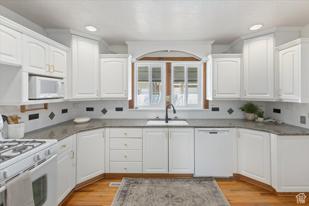 Kitchen featuring white cabinets, sink, light hardwood / wood-style floors, and white appliances