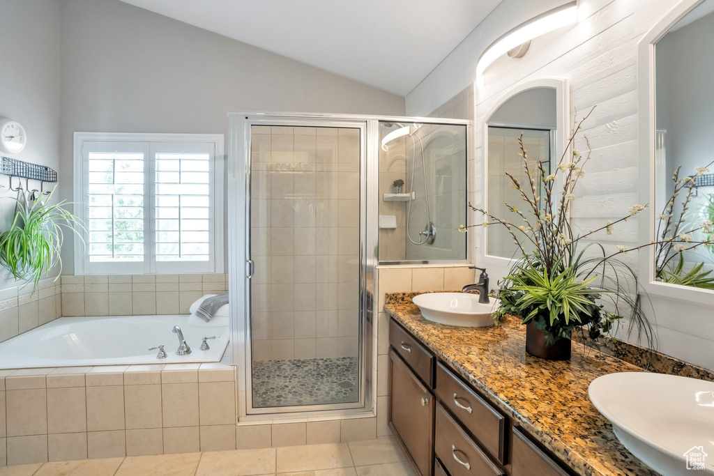 Bathroom with vaulted ceiling, tile floors, double vanity, and separate shower and tub