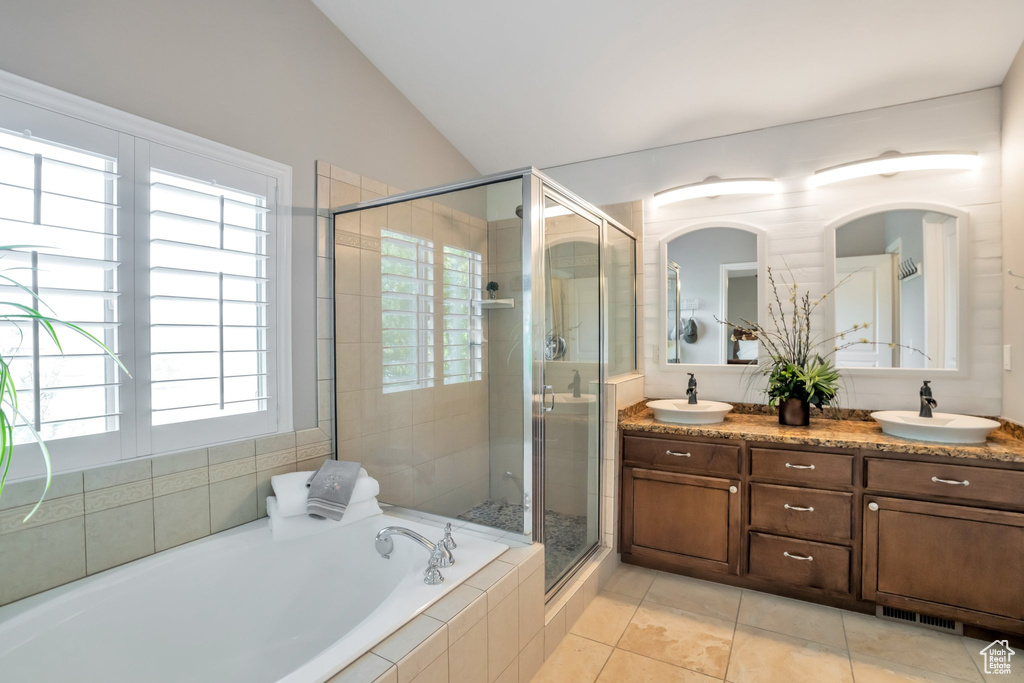 Bathroom featuring tile floors, independent shower and bath, lofted ceiling, and dual vanity