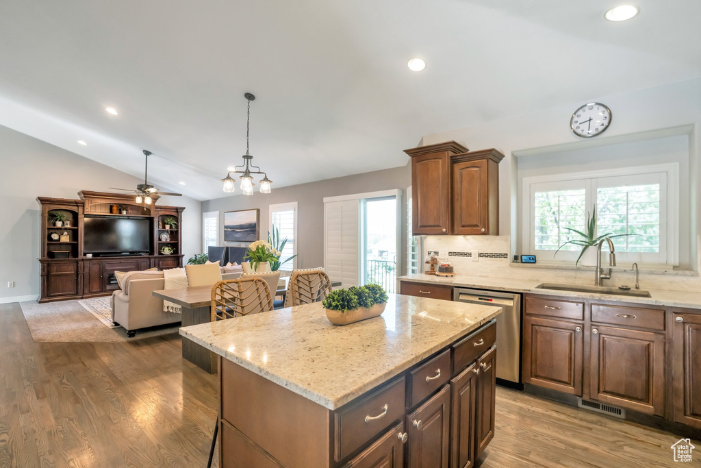 Kitchen featuring hardwood / wood-style floors, backsplash, sink, stainless steel dishwasher, and a kitchen island