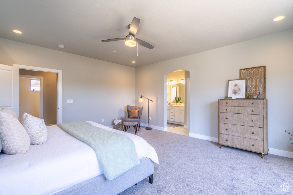 Bedroom with light colored carpet, ceiling fan, and ensuite bathroom