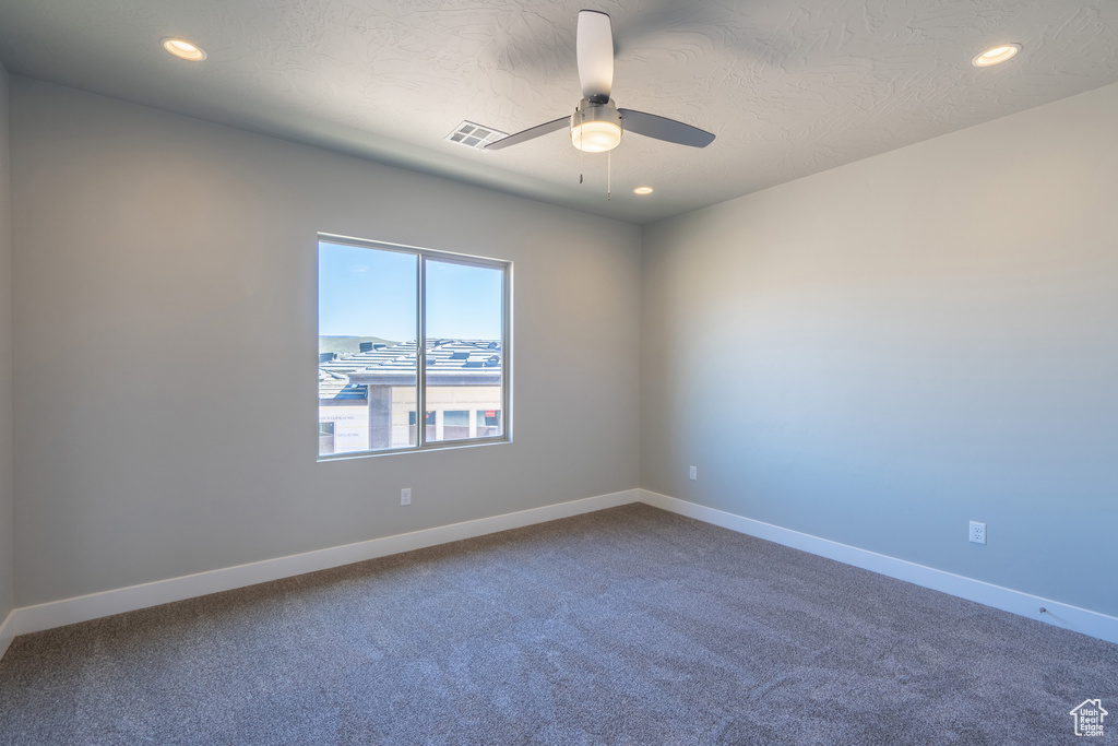 Carpeted empty room featuring ceiling fan and a textured ceiling