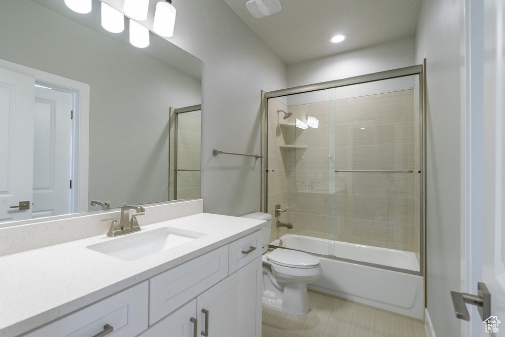 Full bathroom featuring vanity with extensive cabinet space, toilet, enclosed tub / shower combo, and tile flooring
