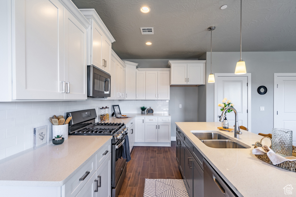 Kitchen featuring pendant lighting, white cabinetry, backsplash, appliances with stainless steel finishes, and sink