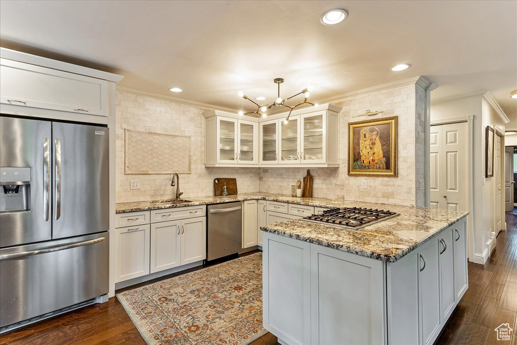 Kitchen with tasteful backsplash, white cabinetry, stainless steel appliances, and dark hardwood / wood-style floors