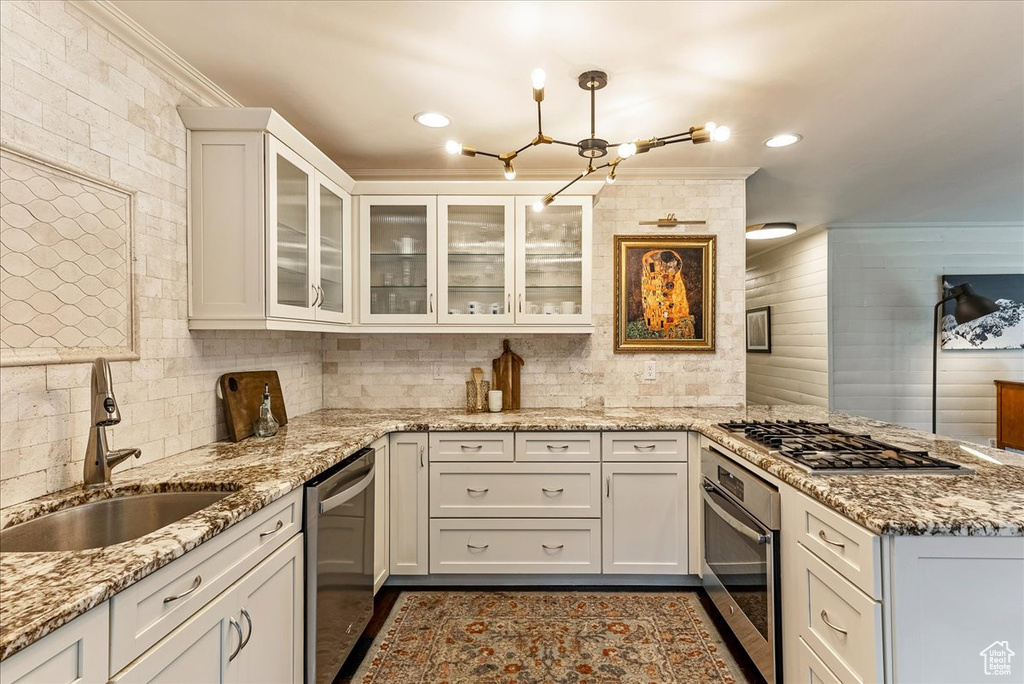 Kitchen with appliances with stainless steel finishes, sink, and light stone countertops
