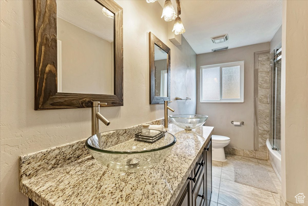 Full bathroom with shower / bathing tub combination, toilet, vanity with extensive cabinet space, and tile flooring