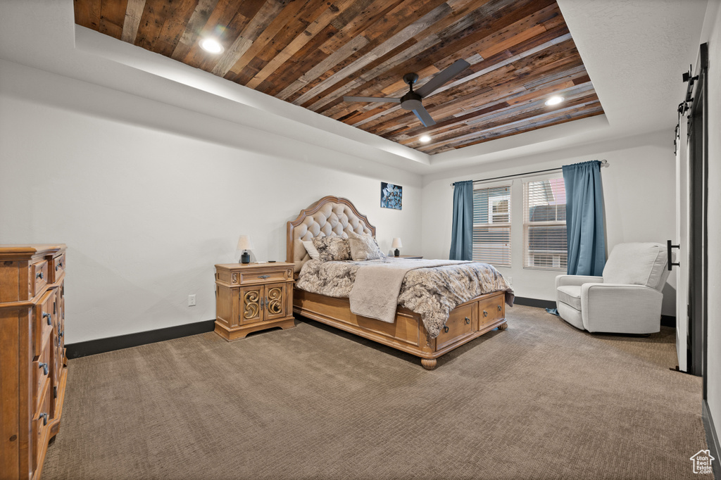 Carpeted bedroom featuring wood ceiling, ceiling fan, and a raised ceiling