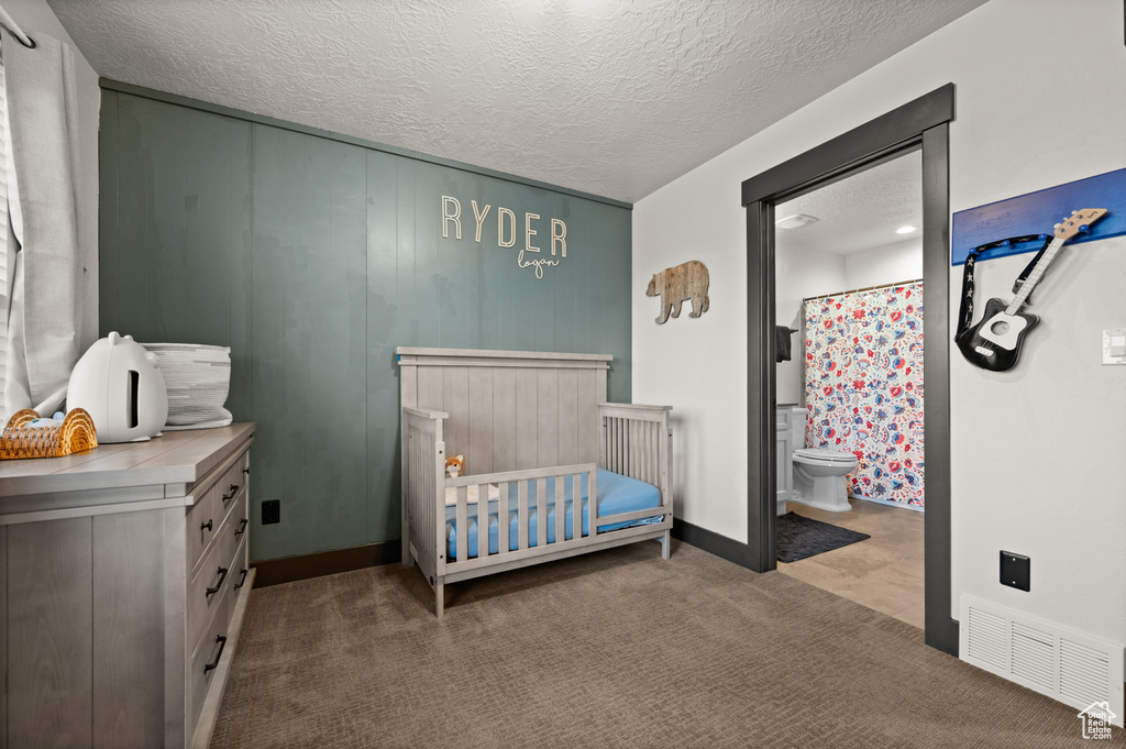Bedroom with ensuite bath, a textured ceiling, and a nursery area