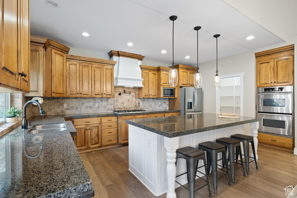 Kitchen with a kitchen island, appliances with stainless steel finishes, dark wood-type flooring, and custom range hood